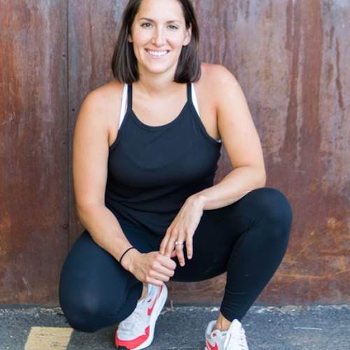 Ariana crouched in an urban setting, smiling and wearing athletic wear.
