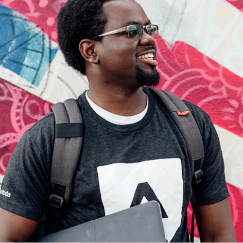 Junior smiling and looking off to the right in front of a red, white and blue striped background.